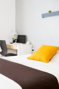 a bed with a yellow pillow and a desk with a laptop at Nerva Accommodation in Rome