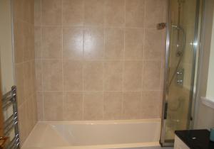 a bathroom with a shower and a white bath tub at Callie's Cottage in North Berwick