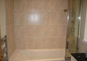a bathroom with a shower and a white bath tub at Callie's Cottage in North Berwick