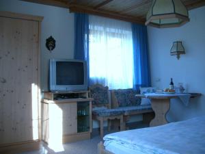 a bedroom with a tv and a couch and a window at Andrea Schmaranzer - Privatzimmer in Gosau