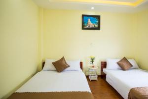 2 łóżka w pokoju z białymi ścianami w obiekcie LuTo Hotel w mieście Da Lat