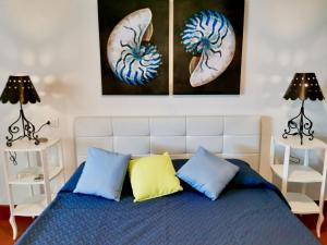 Una cama con almohadas azules y amarillas en un dormitorio en Beachfront House Geremeas Sardegna, en Geremèas