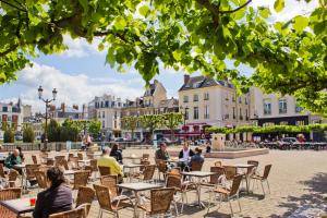Le cœur de Reims, la mairie et le Boulingrin في رانس: مجموعة من الناس يجلسون على الطاولات في ساحة الفناء
