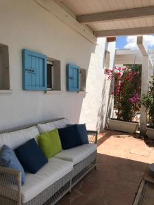 un sofá blanco con almohadas azules y verdes en el patio en Beachfront House Geremeas Sardegna, en Geremèas