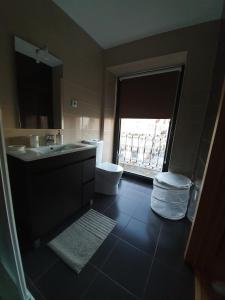 a bathroom with a sink and a toilet and a window at Alojamento 4 Bicas in Seia