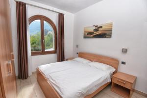 a bedroom with a white bed and a window at Villa San Valentino - Ruculì Hospitality in Tignale