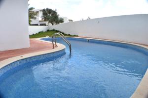 a swimming pool with blue water in front of a house at Villa Amendoeira-POOL HEATED in Guia