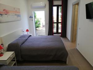 a bedroom with a bed and a tv and a door at Azienda Agrituristica Le Betulle in Riotorto
