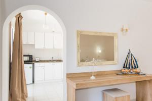 een keuken met witte kasten en een aanrecht met een spiegel bij Emerald Hotel in Malia