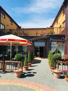 a patio with a row of potted plants and an umbrella at Zajazd Hubus in Grabowo-Olszewo