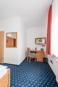 Cette chambre comprend un bureau et une table avec une chaise. dans l'établissement Landhotel Butjadinger Tor, à Nordenham