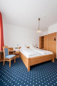 a bedroom with a large bed and a chair at Landhotel Butjadinger Tor in Nordenham