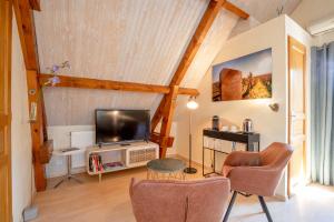 uma sala de estar com uma televisão de ecrã plano e cadeiras em B&B L'Orée du Bois Bourgogne - Adults Only em Saint-Nicolas-lès-Cîteaux