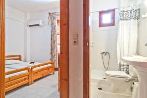 La salle de bains est pourvue de toilettes, d'un lavabo et d'un lit. dans l'établissement Sea Stone Apartments, à Karpathos