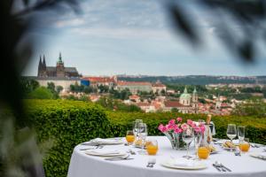 - une table avec des verres à vin et des fleurs roses dans l'établissement Nebozizek Hotel a Restaurant, à Prague