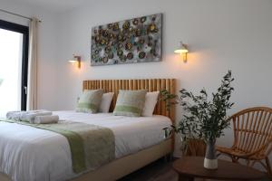 a bedroom with a bed with white sheets and a chair at Hotel Fazio in Bonifacio