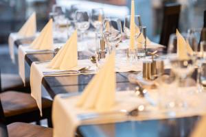 a row of tables with wine glasses and napkins at BNC Hotel - Restaurant - Bowling in Bratislava