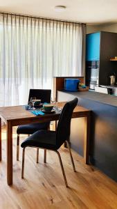 a dining table with a black chair and a kitchen at Loft4two in Meiringen