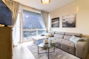 ein Wohnzimmer mit einer Couch und einem Glastisch in der Unterkunft Vanagupes Park Apartments, By Cohost in Palanga