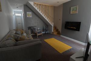 a living room with a couch and a staircase at Madoc Brook Cottage in Conwy