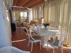 une table et des chaises blanches avec un vase de fleurs. dans l'établissement EDIFICIO CONSULADO, à Calp