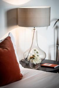 a white vase with flowers sitting on a bed at The Bloomsbury Hotel in London