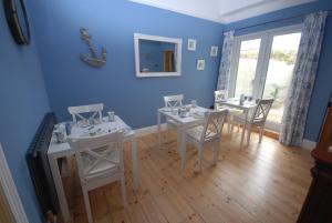 comedor con paredes azules y mesas y sillas blancas en Weymouth Vegan B&B, en Weymouth