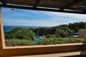 een raam met uitzicht op het zwembad en de oceaan bij Relais Euterpini in Pantelleria