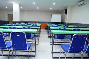 una clase con mesas verdes y sillas azules en RedDoorz At Hotel Gajah Mada Palu, en Palu
