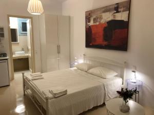 パノルモスにあるGlafki Hotel Tinosの白いベッドと壁に絵画が飾られたベッドルーム1室