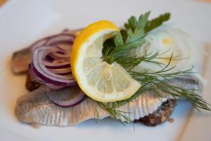 a plate of fish with a lemon on top at Landhotel Butjadinger Tor in Nordenham +23 photos