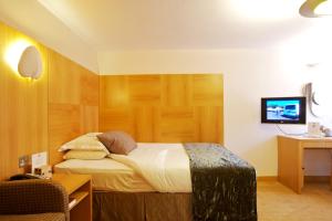 a bedroom with a bed and a tv on a wall at The Pinewood Hotel in Slough