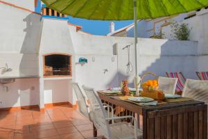 a patio with a table and chairs and an umbrella at SUNNY HOUSE by Stay in Alentejo in Vila Nova de Milfontes
