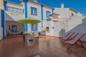 a patio with chairs and an umbrella on a house at SUNNY HOUSE by Stay in Alentejo in Vila Nova de Milfontes