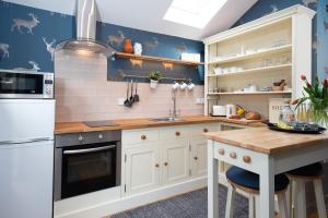 a kitchen with white cabinets and blue walls at Coach House B & B in Alnwick