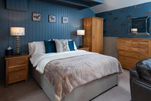 um quarto com uma cama com paredes azuis e uma televisão em Coach House B & B em Alnwick