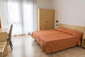 a bedroom with a bed and a desk and window at Hotel Sabrina in Sottomarina