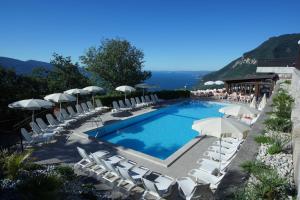 a swimming pool with lounge chairs and umbrellas at Appartamenti Morele in Tignale