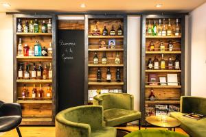a bar with green chairs and bottles of alcohol at Hôtel La Garenne in Saverne