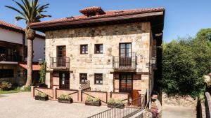 an old stone house with a fence and a palm tree at Apartamentos Los Hidalgos in Santillana del Mar