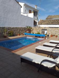 einen Pool mit Liegen und Stühlen neben einem Haus in der Unterkunft Casa De Royal Oaks in Encinas Reales