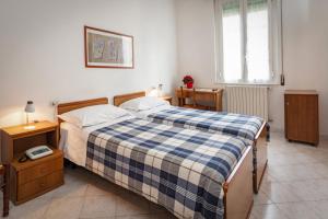 a bedroom with a bed with a blue and white plaid blanket at Albergo Edera in Salsomaggiore Terme