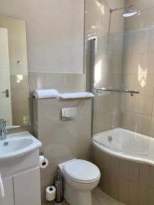 a bathroom with a toilet and a sink and a tub at Hotel AT Hatfield Apartments in Pretoria