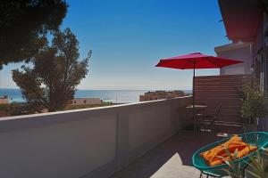 a patio with a table and a red umbrella at SunRise Cassis in Cassis