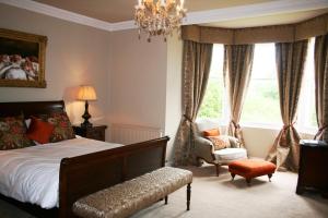 sypialnia z łóżkiem, krzesłem i żyrandolem w obiekcie The Old Parsonage Country House w mieście Berwick-upon-Tweed