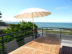 una mesa de madera con una sombrilla en un balcón con vistas al océano en Appartement Roc'h Avel - Front de mer, Vue sur mer et Jardin ensoleillé sans vis à vis, en Le Croisic
