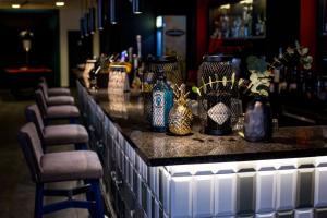 a bar with several vases on a counter with chairs at Vienna House Easy by Wyndham Bucharest Airport in Otopeni