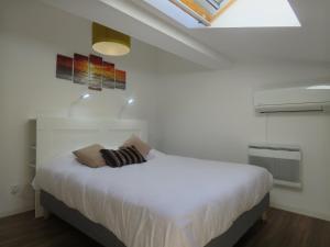 ein Schlafzimmer mit einem weißen Bett und einem Dachfenster in der Unterkunft Appartement centre historique avec Terrasse au porte de la Camargue in Saint-Gilles