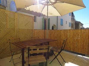 a wooden table and chairs with an umbrella on a balcony at Appartement centre historique avec Terrasse au porte de la Camargue in Saint-Gilles
