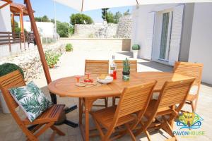 drewniany stół i krzesła na patio w obiekcie Pavon House Green - Villetta nuova costruzione 80 mt dal mare, 3 km da spiagge Torre San Giovanni w mieście Capilungo